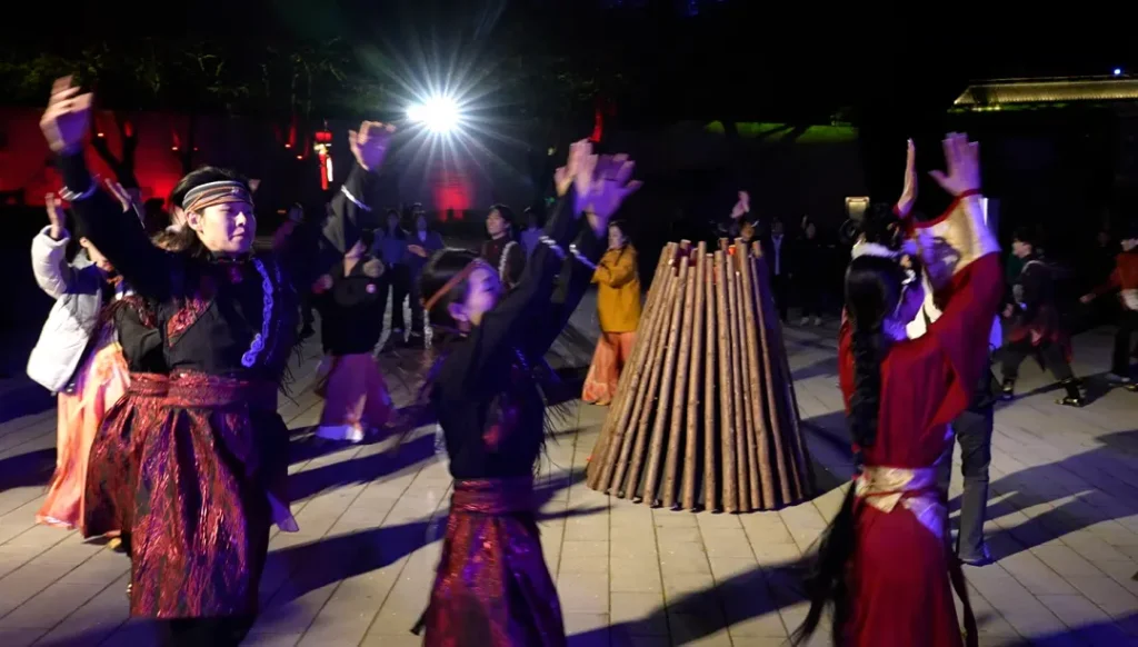 The performers are dancing around a bonfire in the wilderness.